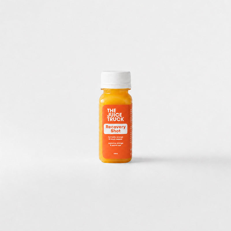 A shot bottle of turmeric juice from The Juice Truck, featuring a white cap and an orange label, set against a clean white background.