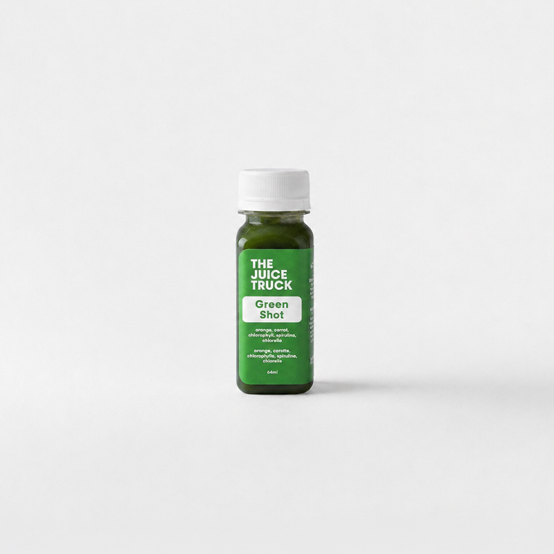 A small bottle of The Juice Truck Green Shot juice with a white cap, centered on a clean light gray background.