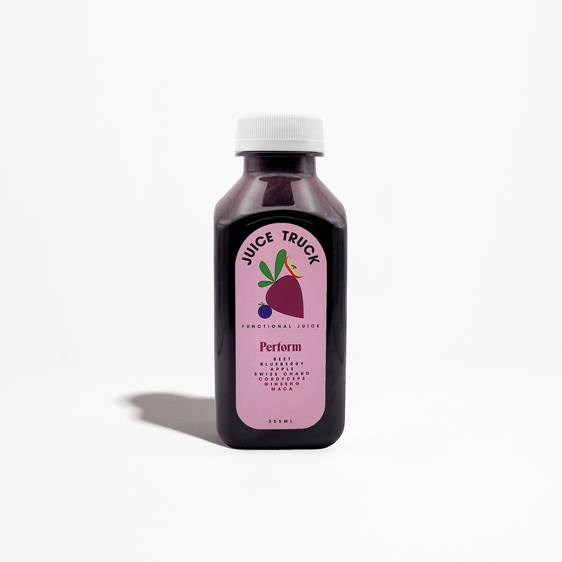 A bottle of 'Juice Truck' branded juice with a label that shows 'Perform' and images of a beet, blueberry, apple, and Swiss chard. The bottle is dark and the liquid inside is purple.