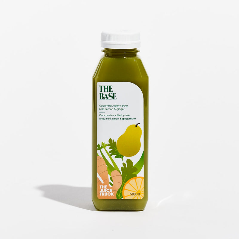 A bottle of juice labeled 'THE BASE' with illustrations of a kale leaf, lemon, and ginger, indicating the flavours of the juice.